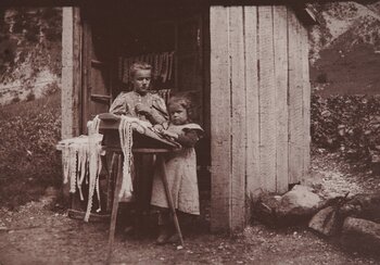 Spitzen herstellen und verkaufen geht im Berner Oberland um 1900 Hand in Hand. Mädchen klöppeln in einem Verkaufsstand im Lauterbrunnental am Strassenrand und bieten gleichzeitig ihre Spitzen feil. Ihre Kundschaft sind Touristinnen und Touristen, die damals noch in einer Kutsche vorbeiziehen. Schweizerisches Nationalmuseum
