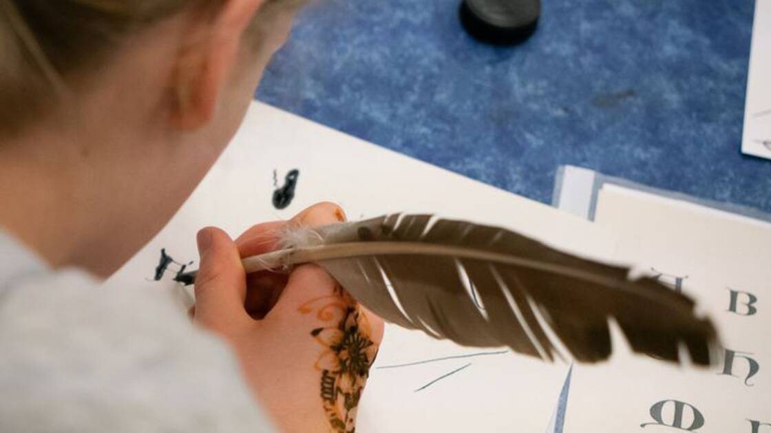 A child writing with pen and ink during a workshop.