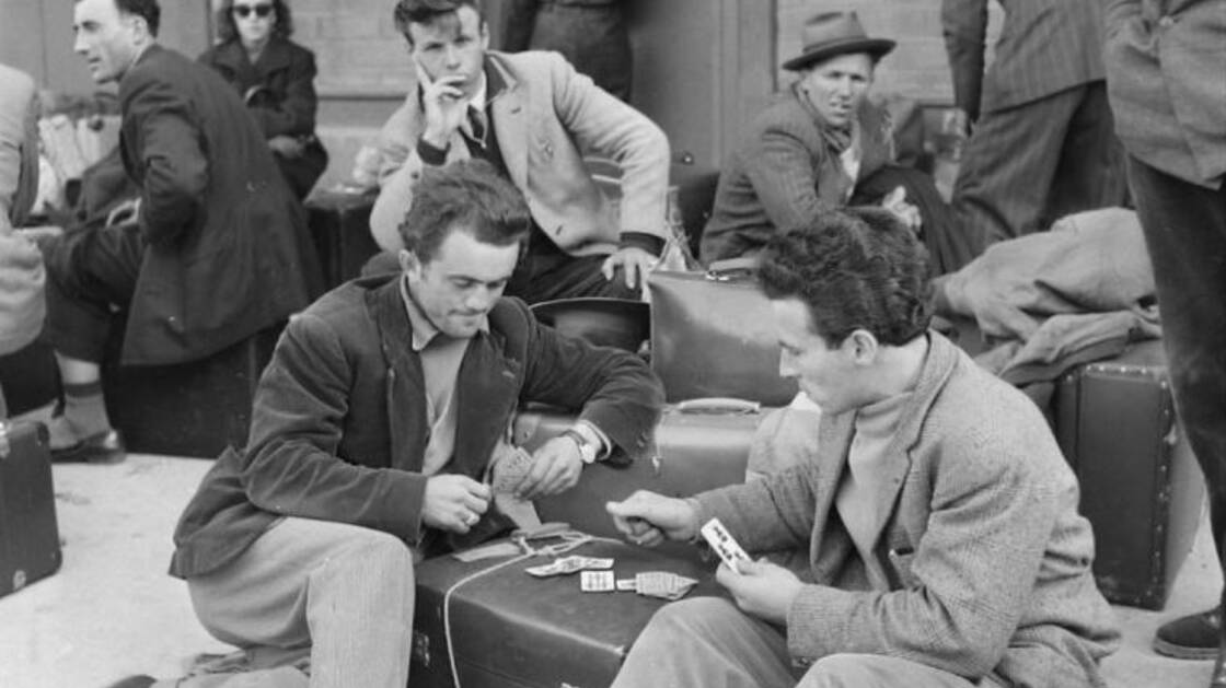 Photographie historique de migrants attendant à la gare avec leurs bagages.