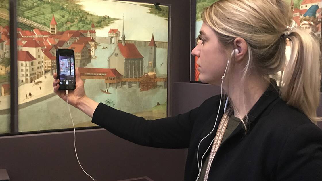Vermittlungsperson mit iPhone während einer Virtuellen Führung.