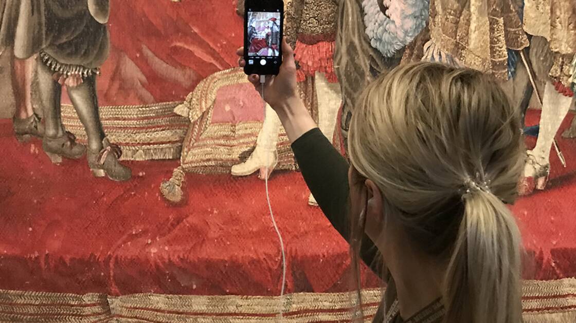 Vermittlungsperson mit iPhone während einer Virtuellen Führung.