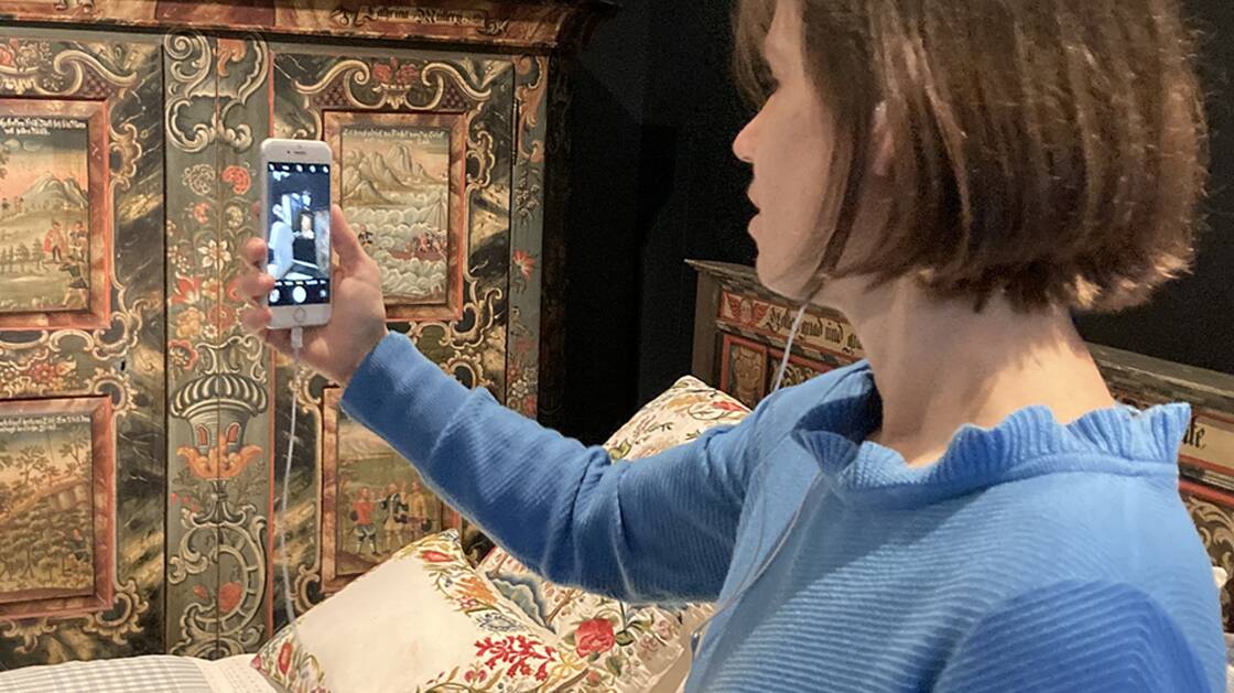 Vermittlungsperson mit iPhone während einer Virtuellen Führung.