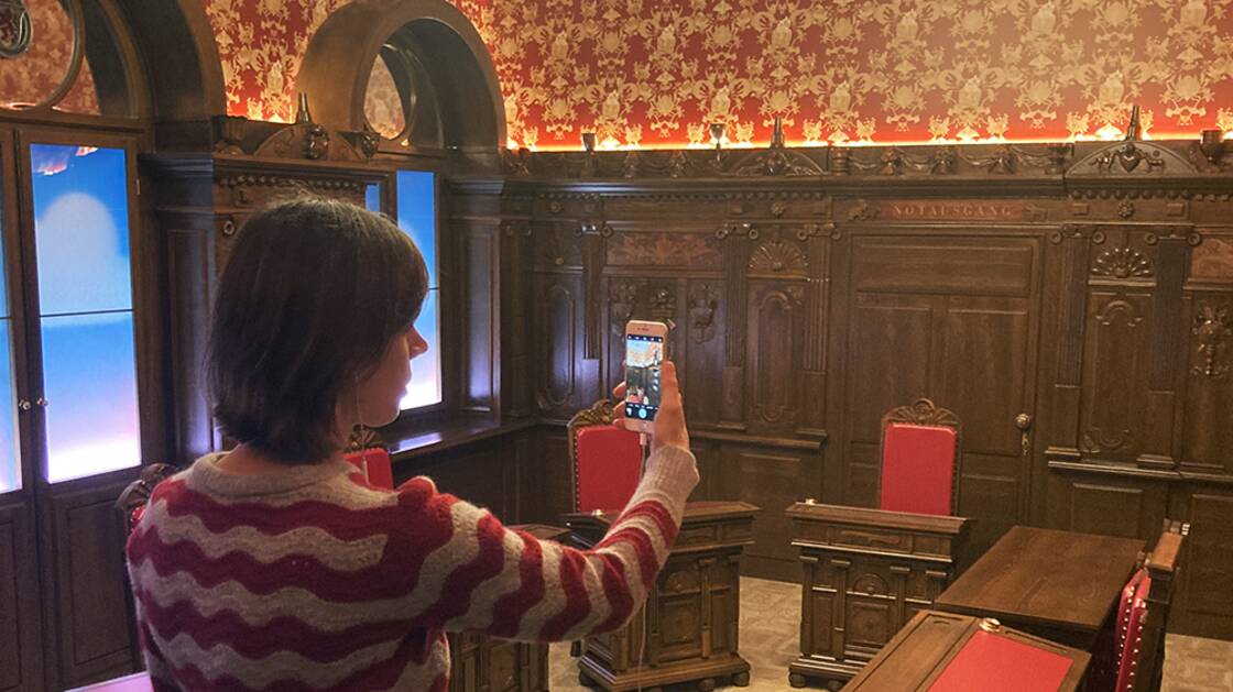 Vermittlungsperson mit iPhone während einer Virtuellen Führung.