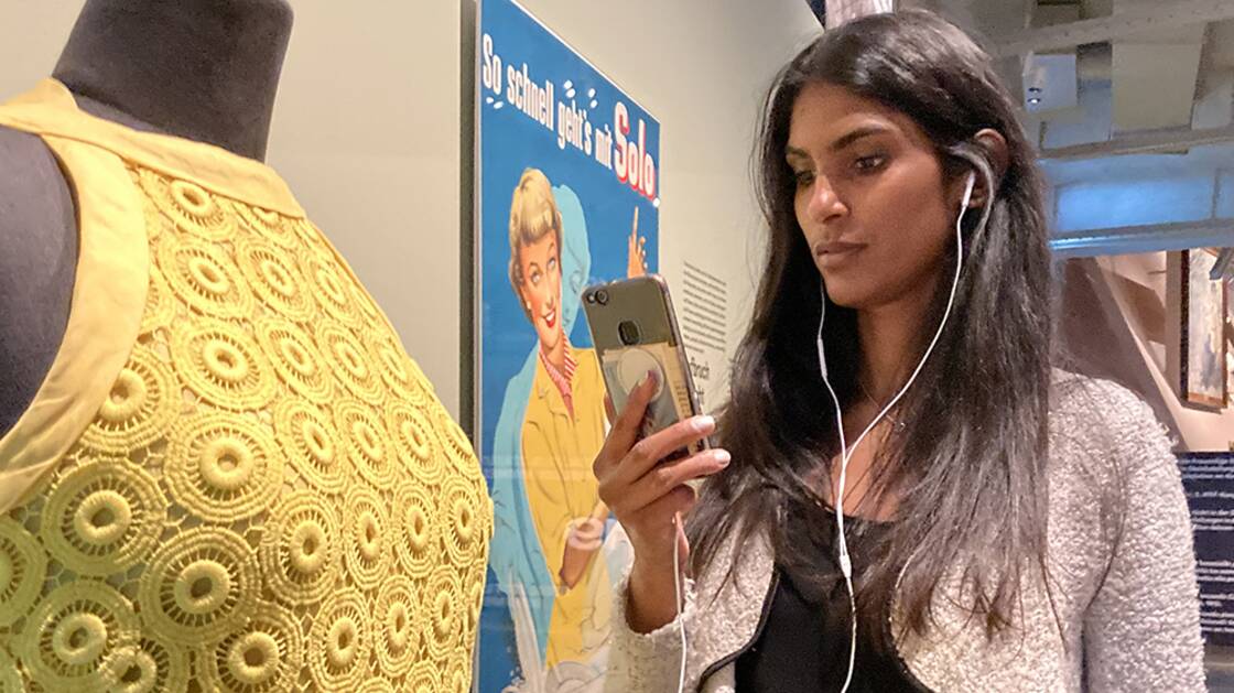 Vermittlungsperson mit iPhone während einer Virtuellen Führung.