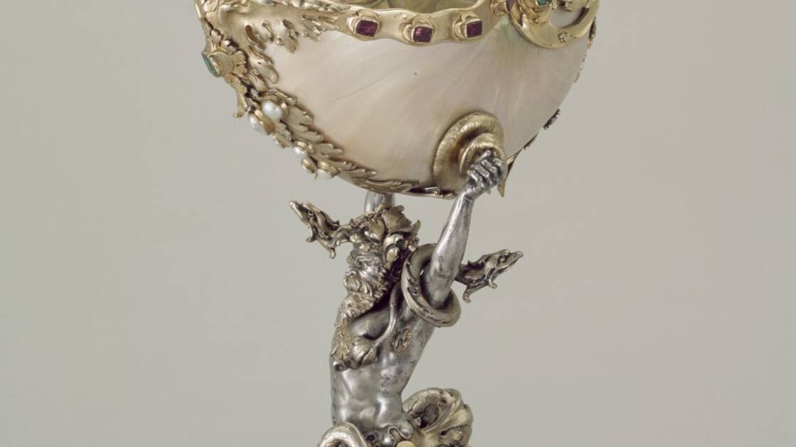 Pokal mit Triton, der einen Nautilus in den Händen hält. Kreation des Goldschmieds Johann Karl (Silvan) Bossard, in barockem Stil. Silber, teilvergoldet, mit Smaragden, Granat und Naturperlen. Um 1900.